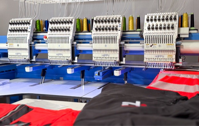 Atelier de marquage SIP19 à Marne-la-Vallée : rangée de machines à broder multi-têtes HAPPY en cours de broderie sur des vêtements de travail